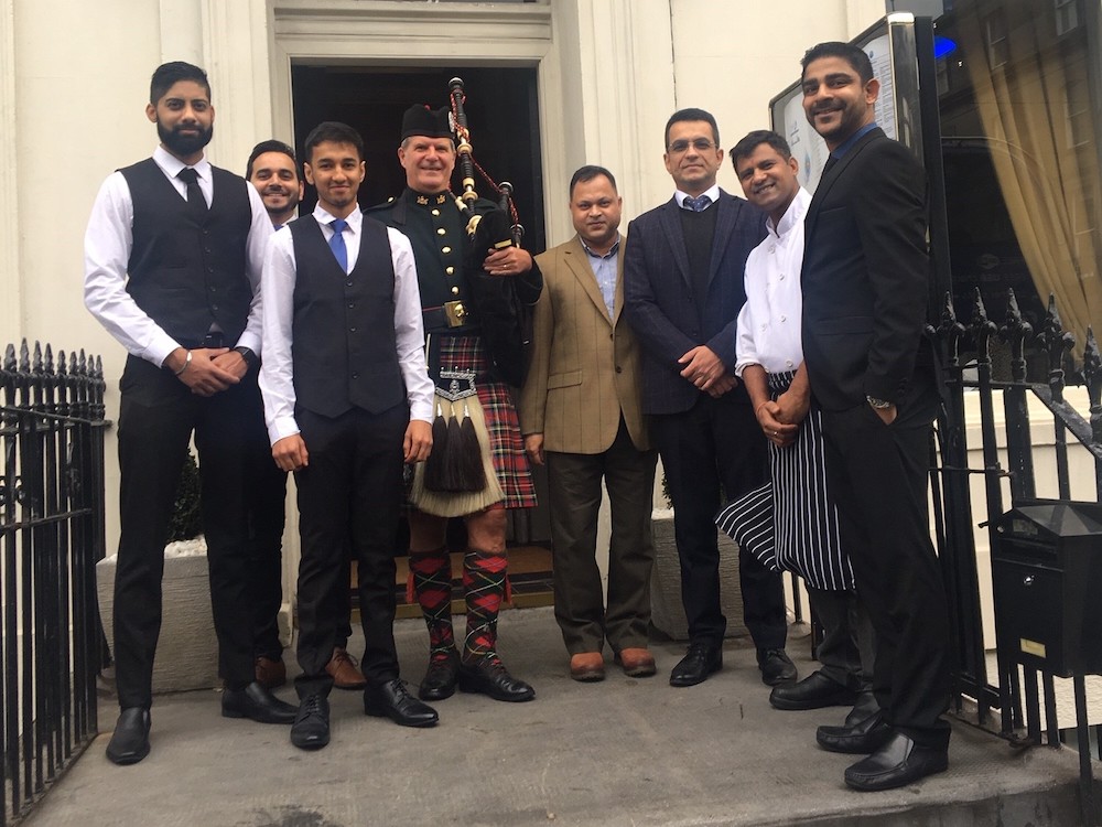 Owners of Mumbai Diners Club pose with a piper at the launch of the new restaurant