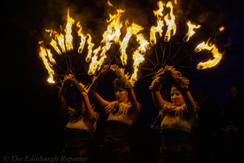 Three women with fiery hoops in front of blue castle