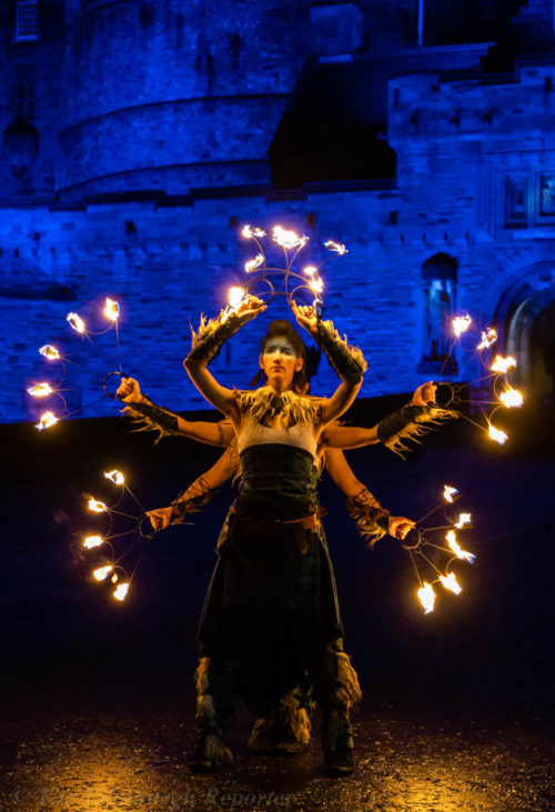 Three women with fiery hoops in front of blue castle