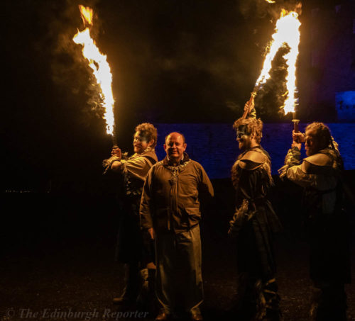 Four men with fiery swords in front of blue castle