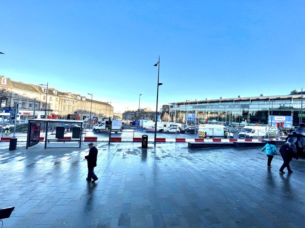 View of roadworks and tramworks at Picardy Place with large compound where workers have parked vans and cars. Blue sky - taken from the steps of St Mary's Cathedral where a new bus stop has been formed