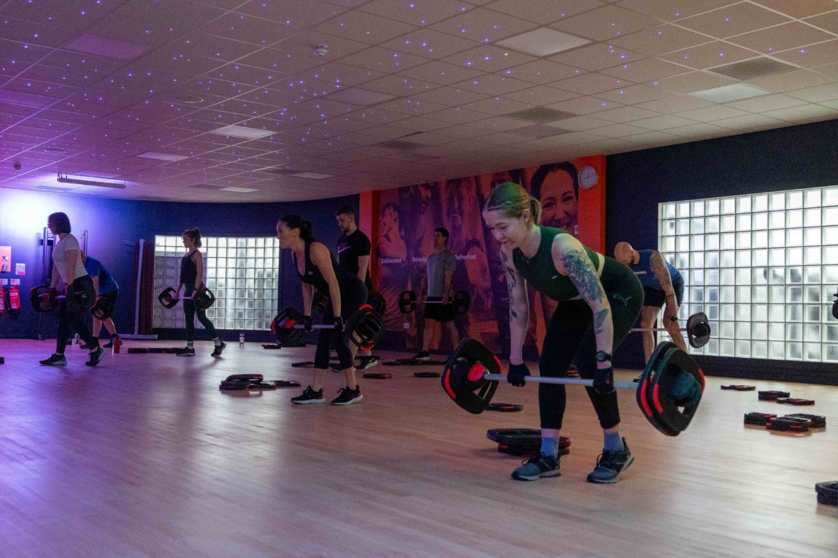 Woman in a fitness class lifting a weights bar