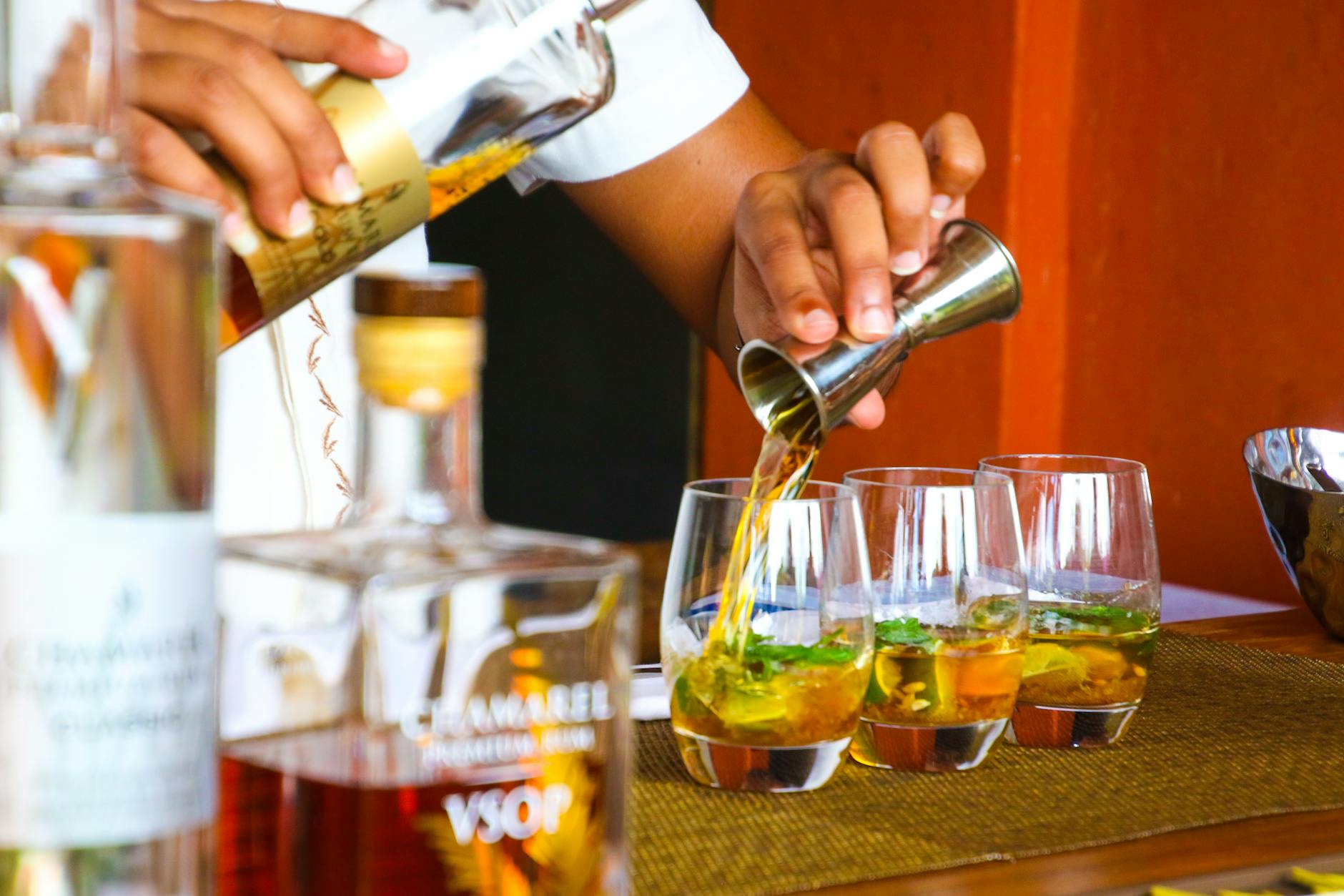 person poring cocktail on clear drinking glass