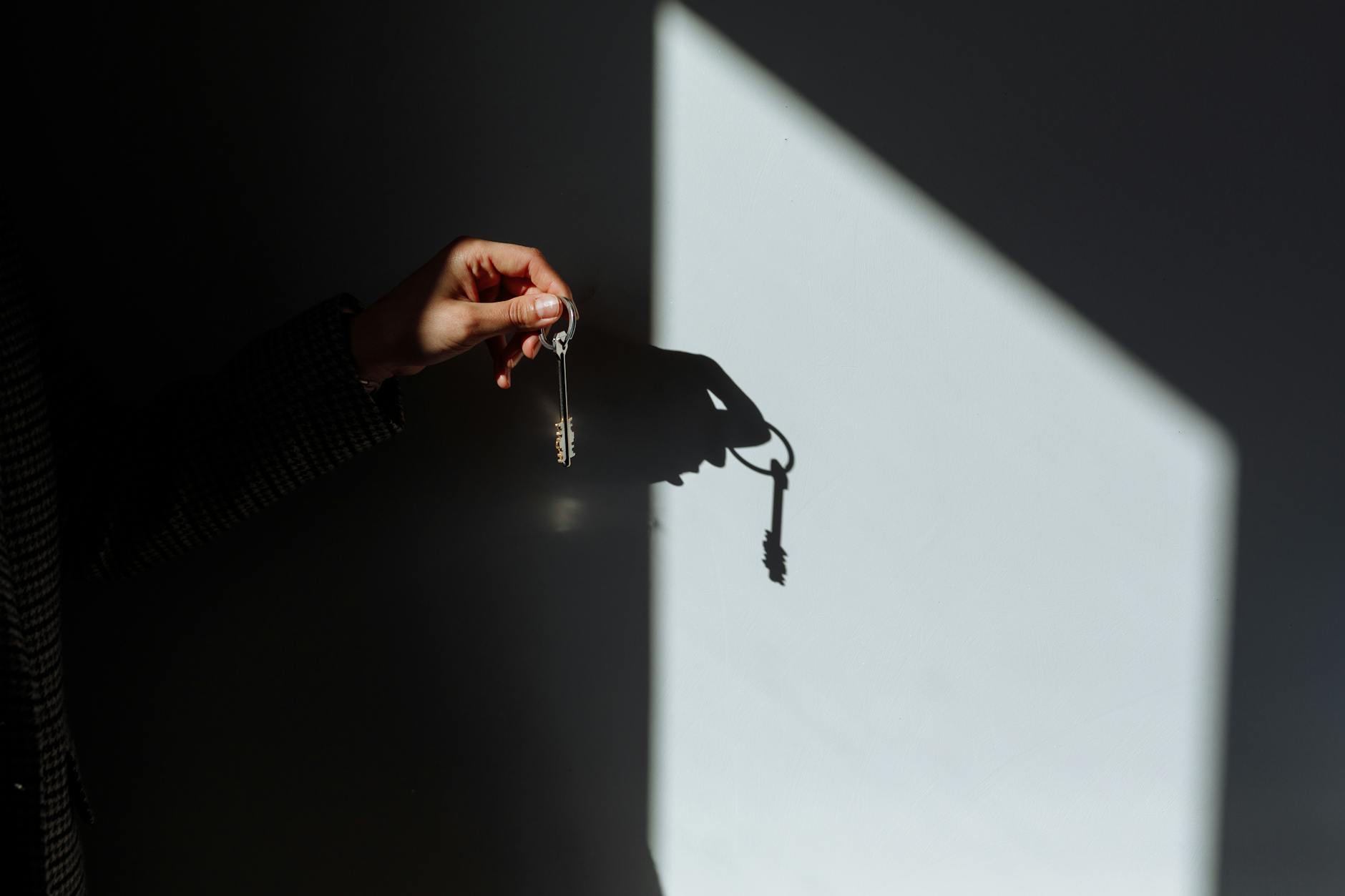 shadow of a hand holding a key on wall